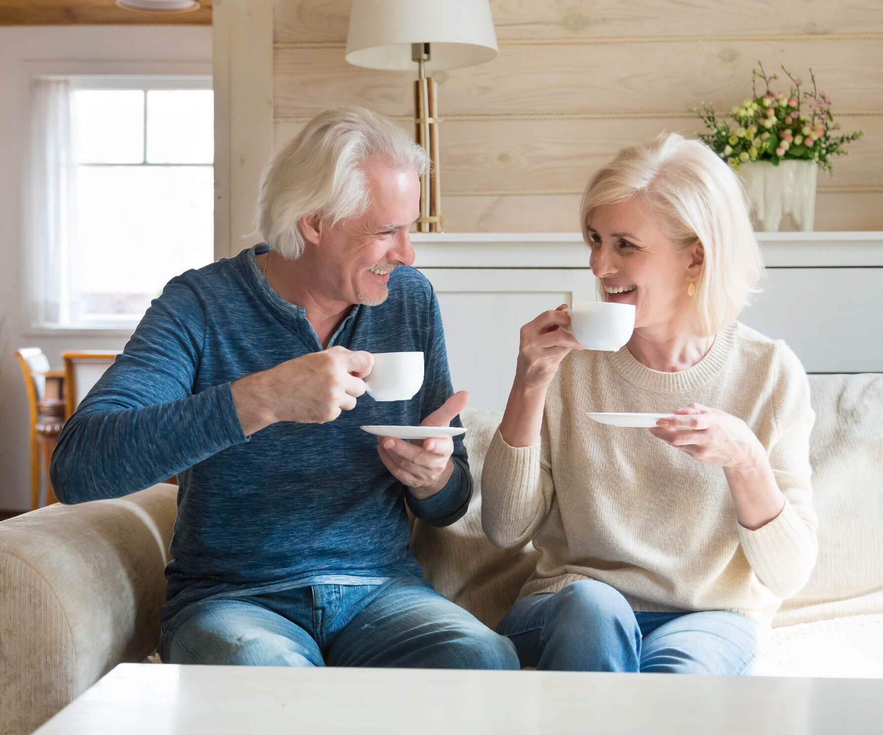 Happy senior couple talking having fun enjoying tea at home